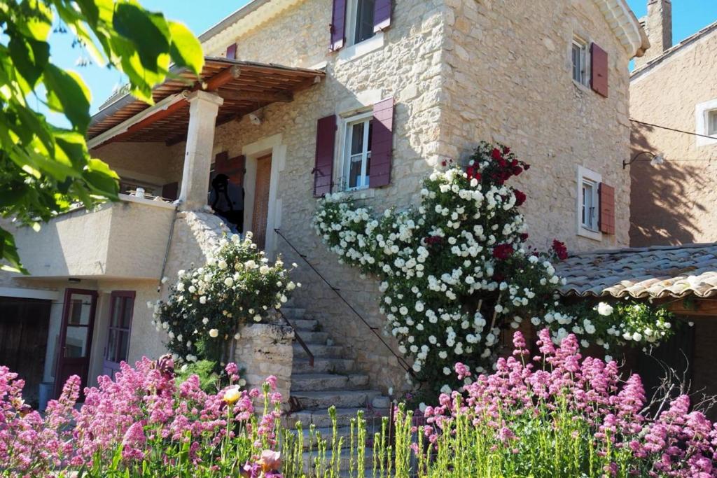 a stone house with flowers in front of it at Le Clos Lau-Tave Charming 110 m Provençal home with private garden in Simiane-la-Rotonde