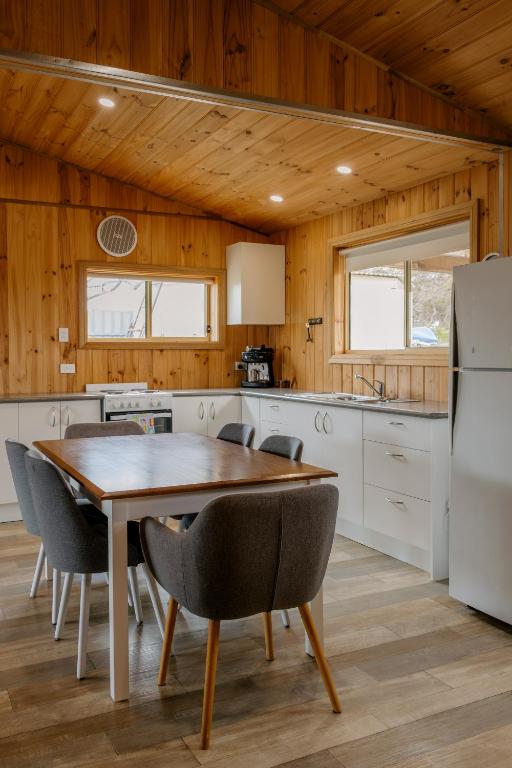 a kitchen with a table and chairs and a refrigerator at Sampsons Shack in Vivonne Bay