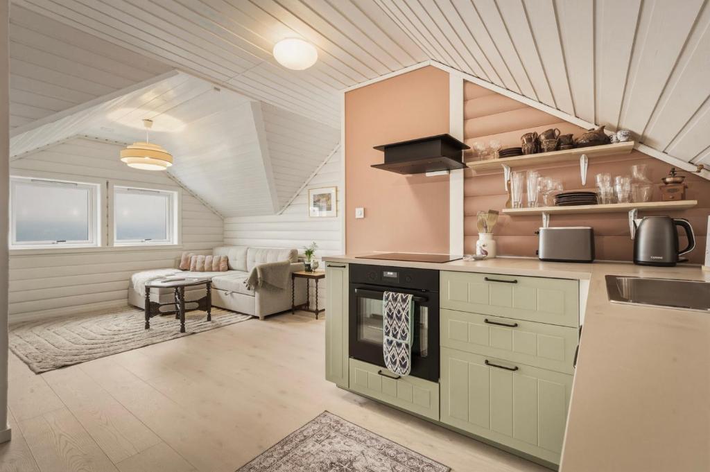 a kitchen with a stove top oven next to a living room at The Nordic Loft in Bergen