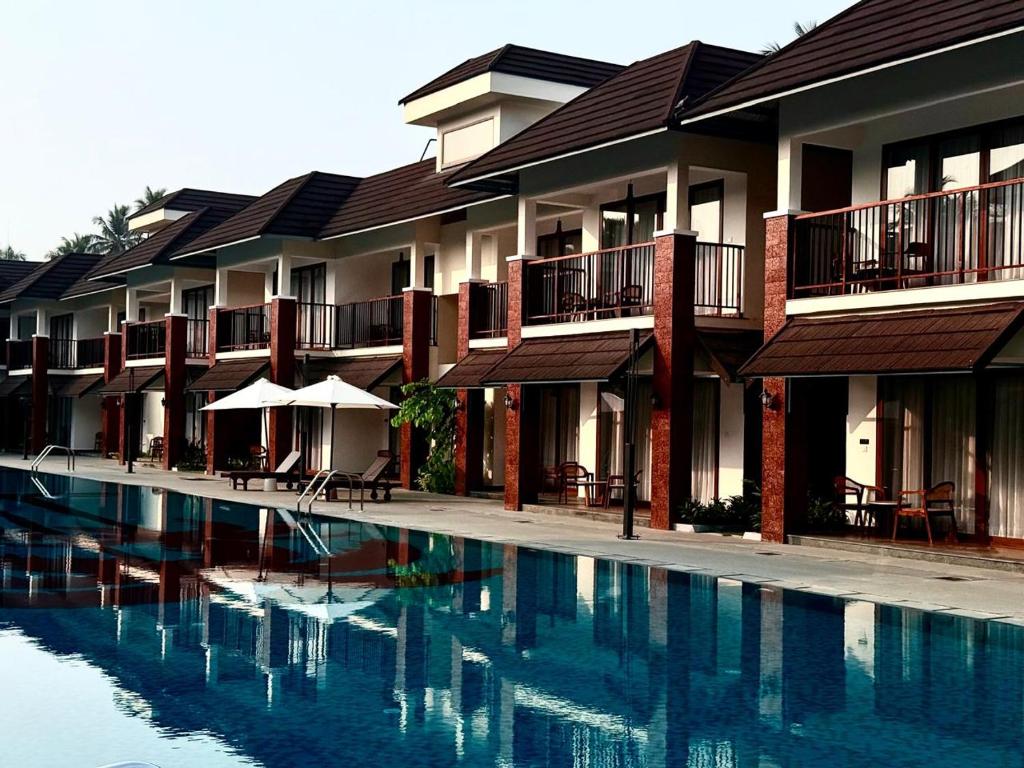 a hotel with a swimming pool in front of a building at KTDC Malabar Courtyard in Mulappilangād