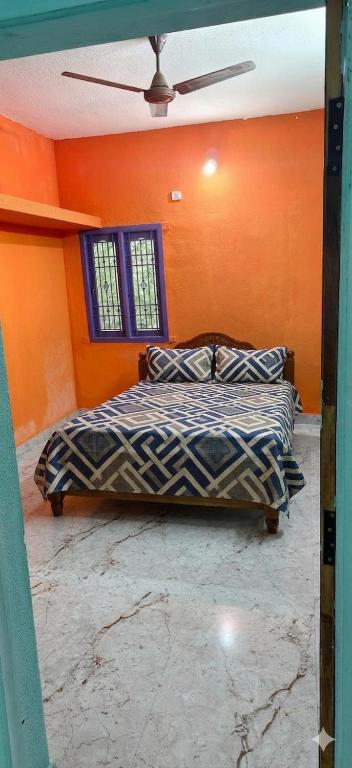 a bedroom with orange walls and a bed with pillows at Girivalam Nest in Jāmb