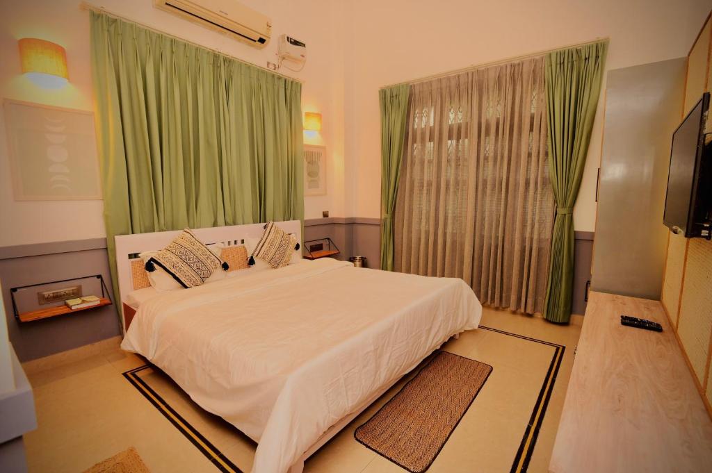 a bedroom with a large white bed with green curtains at Hotel Gargo Tower in Guwahati