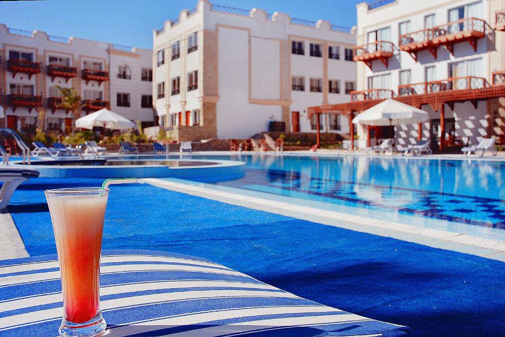 a drink sitting on a table next to a swimming pool at Falcon Naama Star Hotel in Sharm El Sheikh