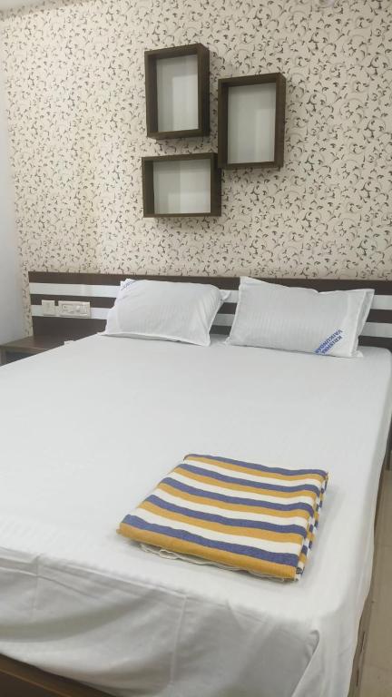 a white bed with a striped pillow on it at Krisna vykundam in Guruvāyūr