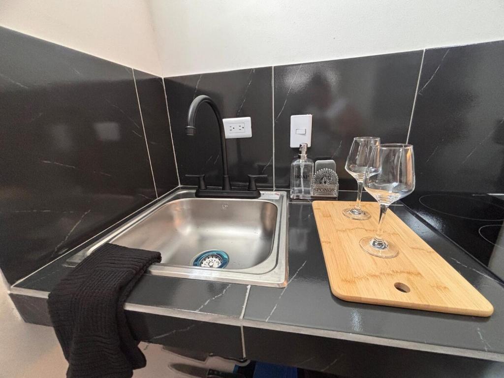 a kitchen counter with a sink and two wine glasses at Downtown, Comfortable Loft, in Hermosillo