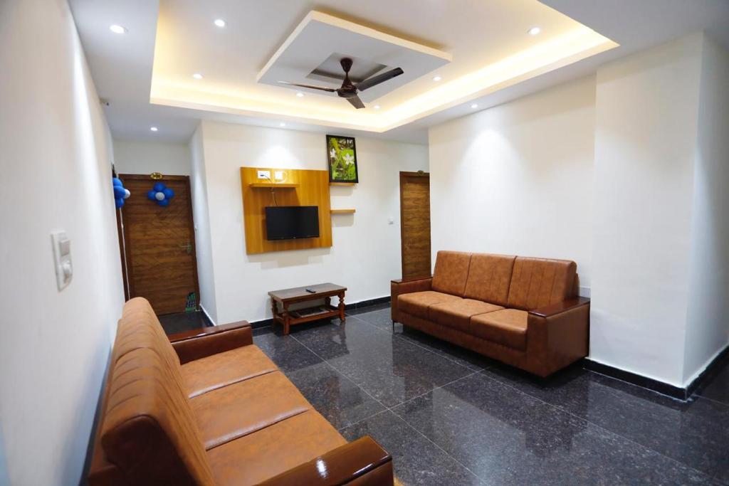 a living room with a couch and a tv at Mantra Lodge in Shimoga