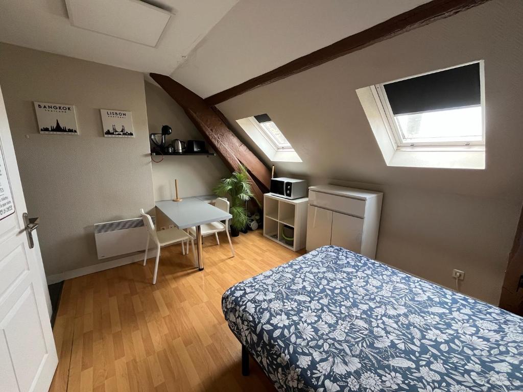 a bedroom with a bed and a table and a window at Studio rénové gare Dijon in Dijon