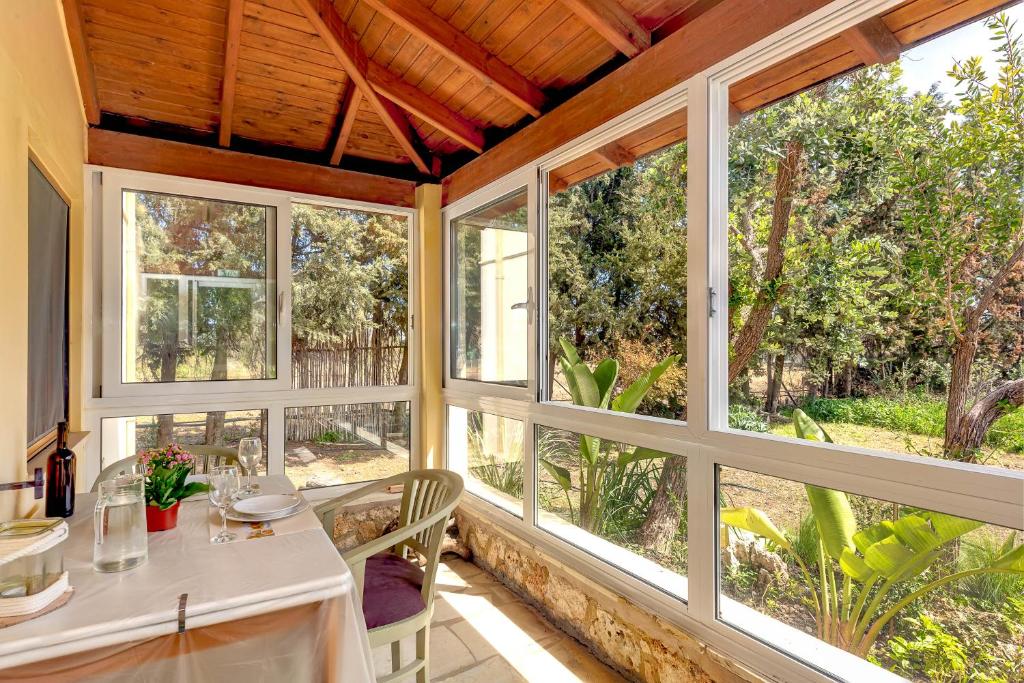 a room with large windows and a table and chairs at Astrelis Emerald Villa - Cozy House Walking Distance to the Beach in Kalyves