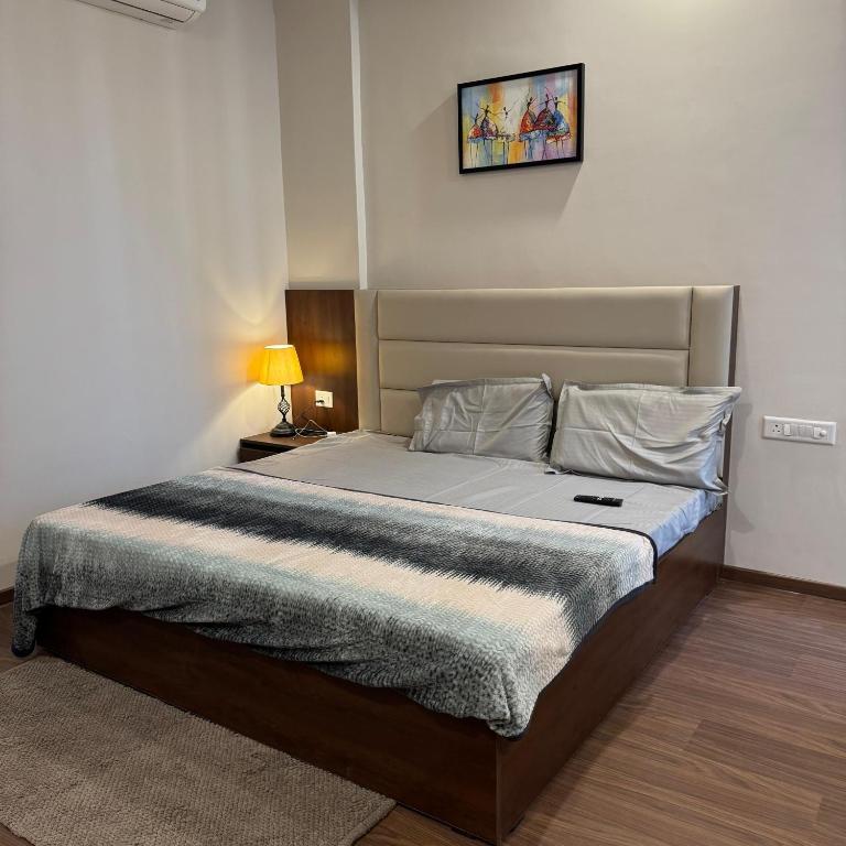 a bedroom with a bed in a room with a lamp at Stayverse noida in Greater Noida