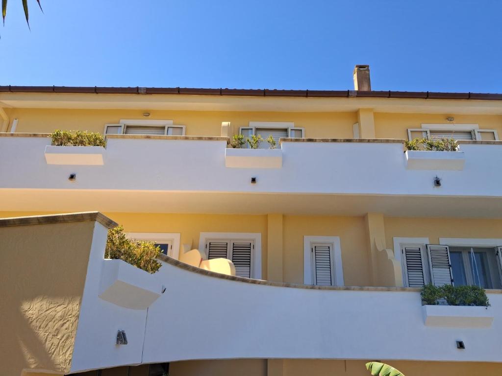 an apartment building with white balconies and potted plants at Affittacamere casagalez in Santa Domenica