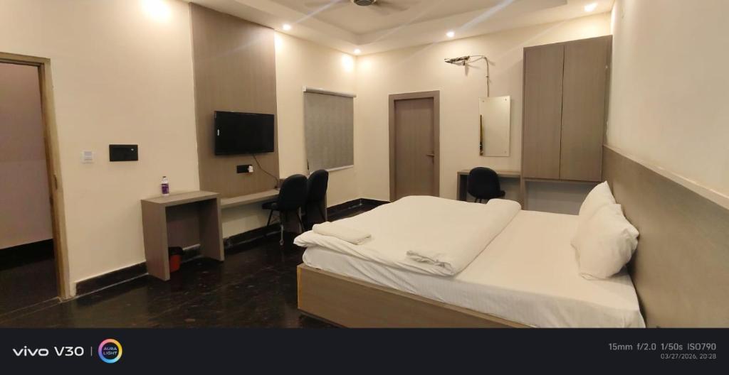 a room with a bed and a desk and a television at Hotel Peepal in Noida
