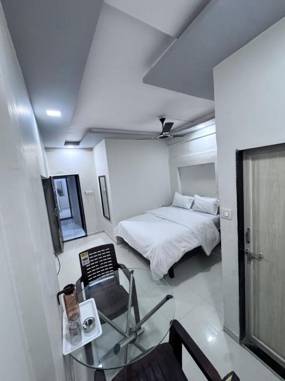 a small bedroom with a bed and a glass table at Radha Krishna Guest House in Surat