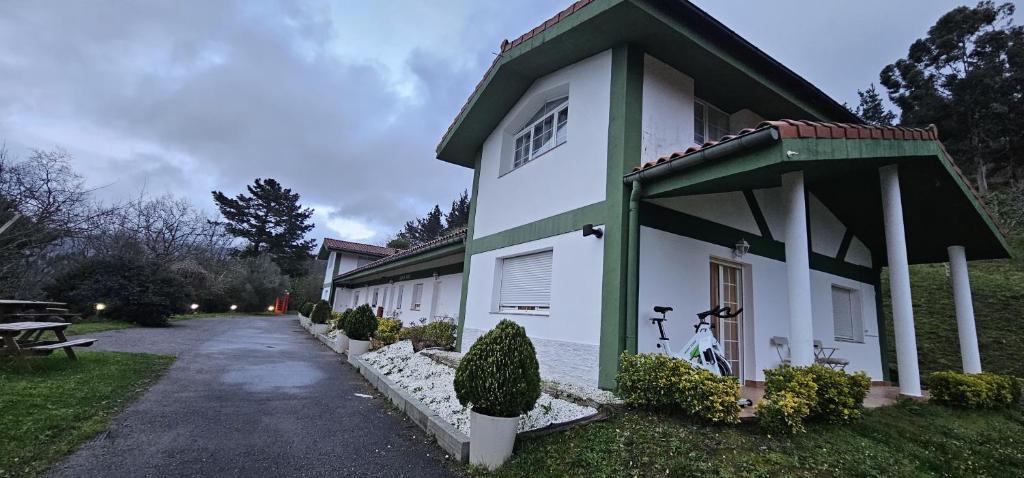 a white building with a green roof and a driveway at LURRA Tierra Apartamento 1 in Sopuerta