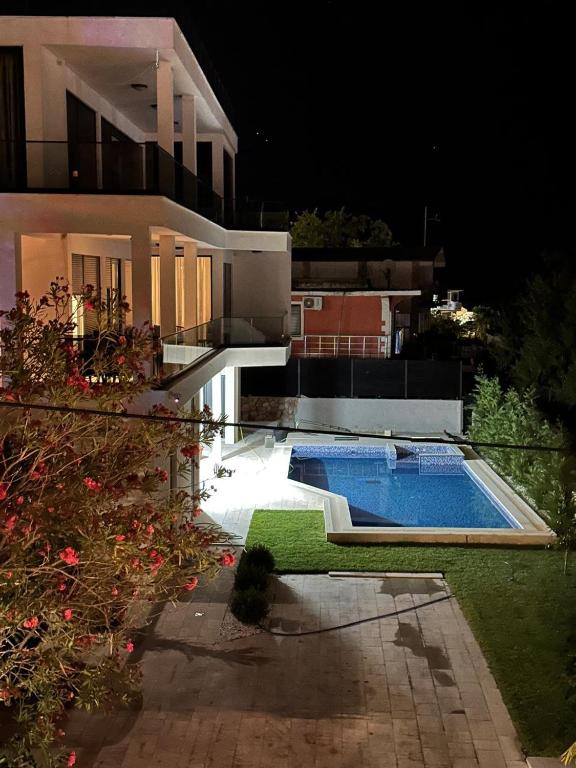 a swimming pool in front of a house at night at Villa Mr Richard in Sutomore