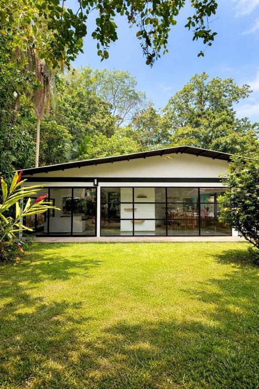 a modern house with glass windows and a yard at Luxury Riverfront House 3BR BBQ Jungle views & walk to river in Parrita