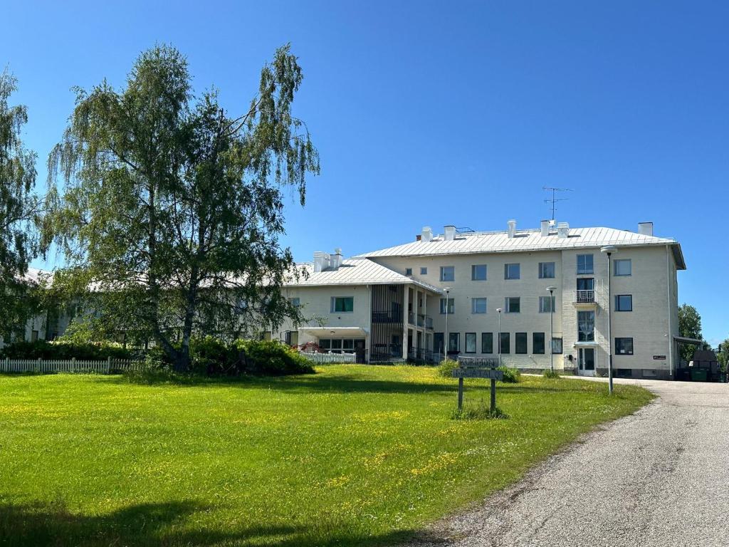 a large white building with a grass field in front of it at Kurimon Majatalo in Kianta