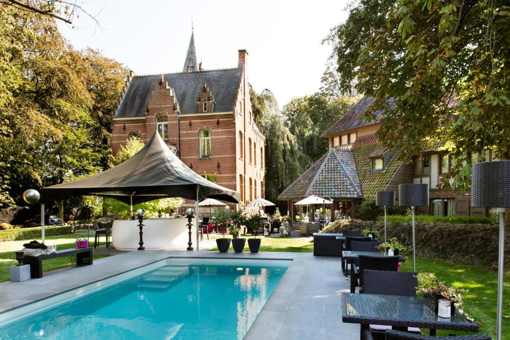 une piscine en face d'un bâtiment dans l'établissement Charmehotel Manoir Ogygia, à Poperinge