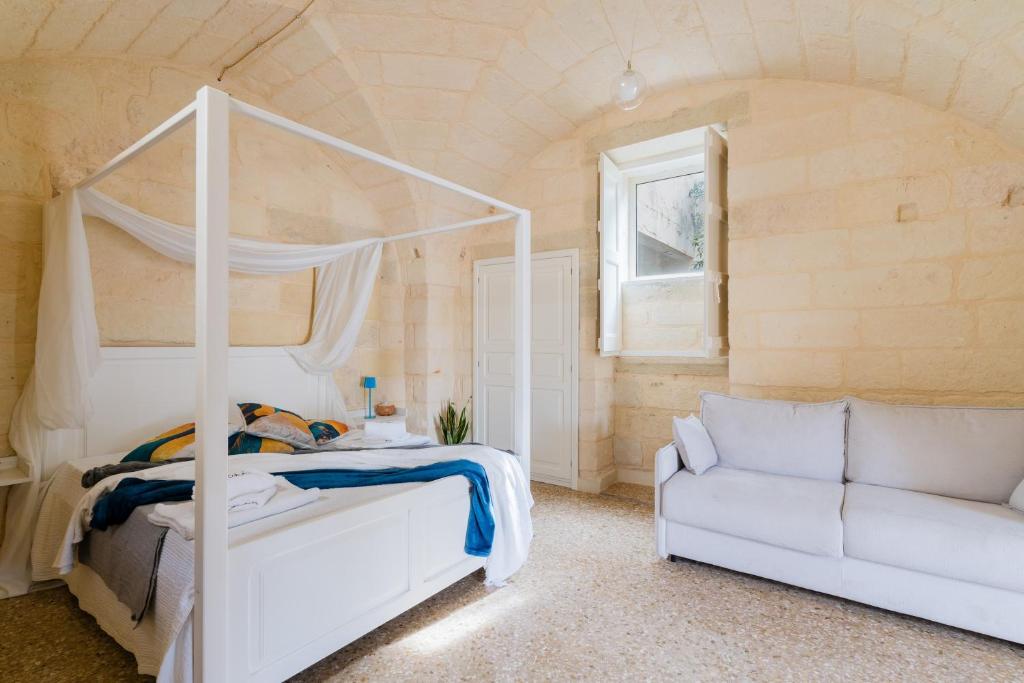 a bedroom with a white bed and a couch at Corte Cochlea Lu Sciardinu Suite in Cannole