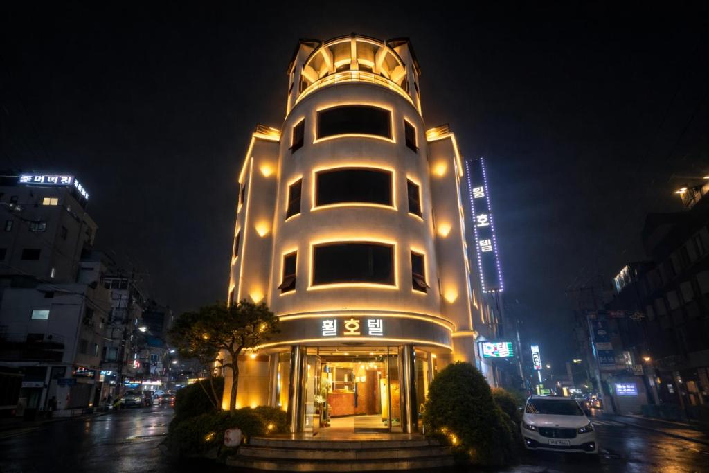 a tall white building with lights on a city street at Gangneung Wheel Hotel in Gangneung