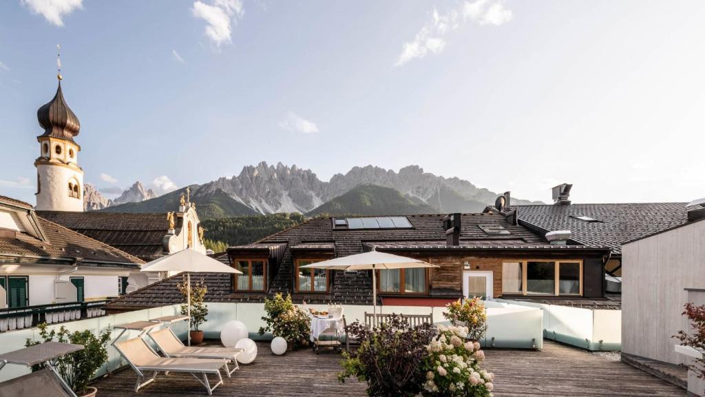 a house with a patio with mountains in the background at Boutique & Gourmet Hotel Orso Grigio - Grauer Bär in San Candido