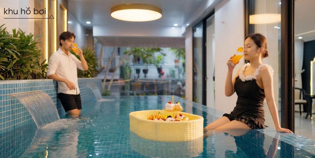 a man and woman eating food in a swimming pool at Bailey Hotel Hue in Hue