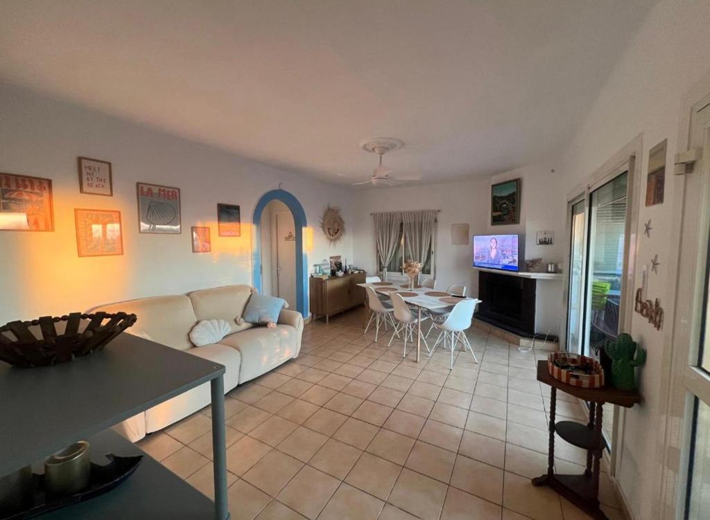 a living room with a white couch and a table at Maison 5 chambres front de mer classée 3 étoiles tourisme in Narbonne