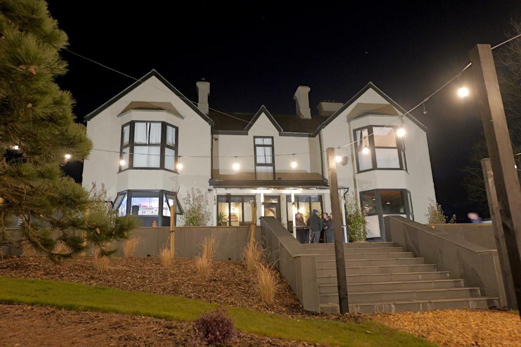 a large white house with people standing outside at night at The Tall Trees Hotel in Amlwch