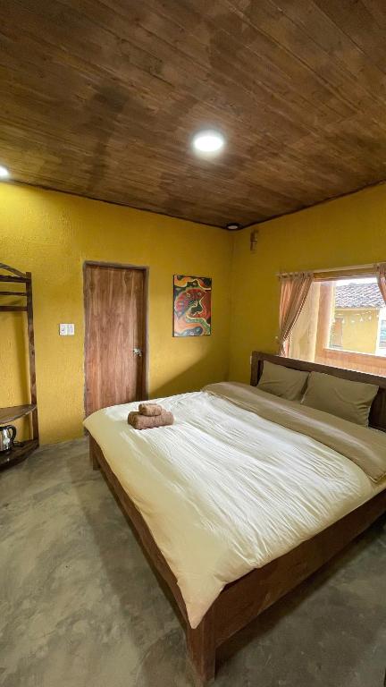 a large bed in a room with a yellow wall at LoLo Hideaeay in Dồng Văn