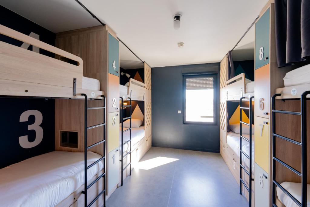 a room with three bunk beds and a window at SLO HOSTEL Bordeaux in Bordeaux