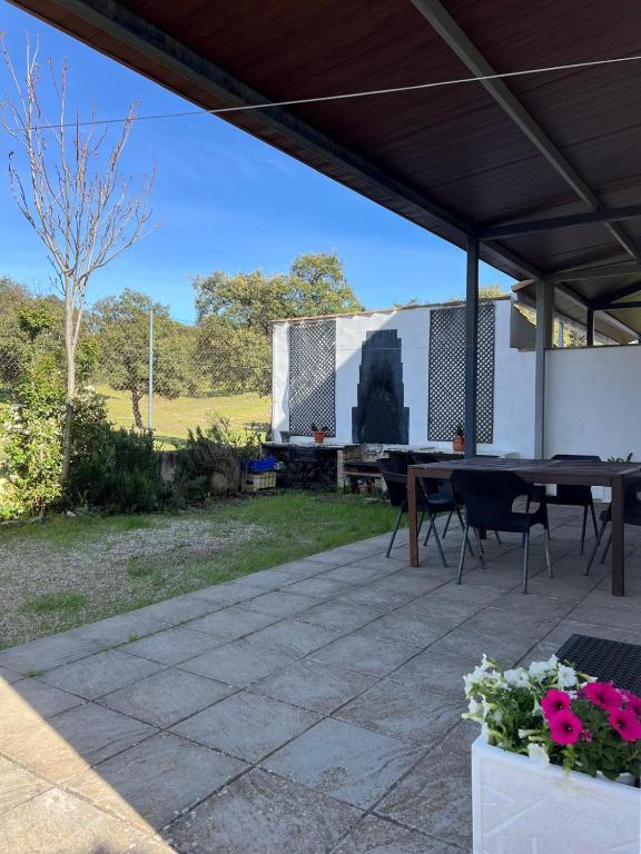 a patio with a table and chairs and a trailer at Casa Rural Nacimiento del Hueznar - Tomillo 17 in San Nicolás del Puerto