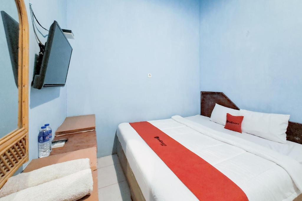 a bedroom with a bed and a flat screen tv at RedDoorz at Arca Hostel Lampung in Lampung