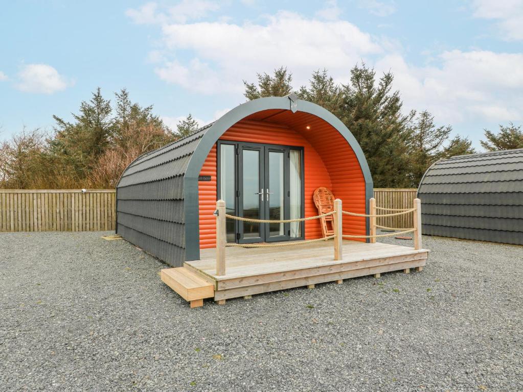 ein orange-graues Kuppelhaus mit Holzterrasse in der Unterkunft Keith in Stranraer