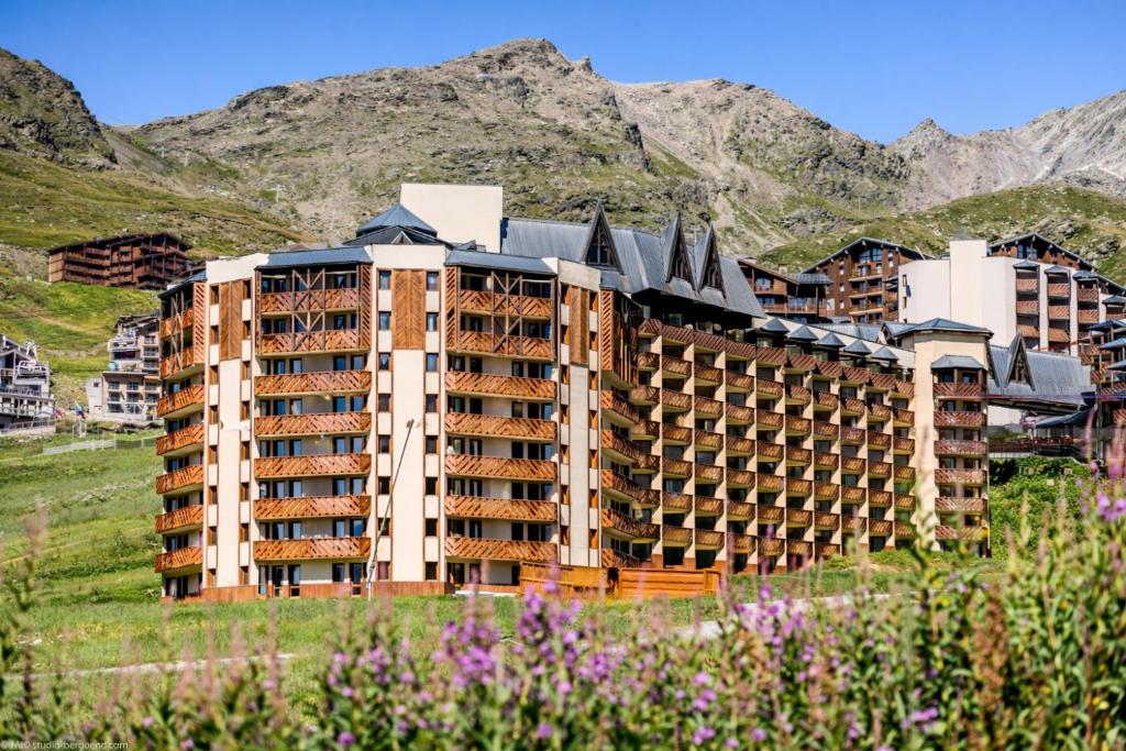 a building in a field with mountains in the background at Résidence Pierre & Vacances Les Temples du Soleil in Val Thorens