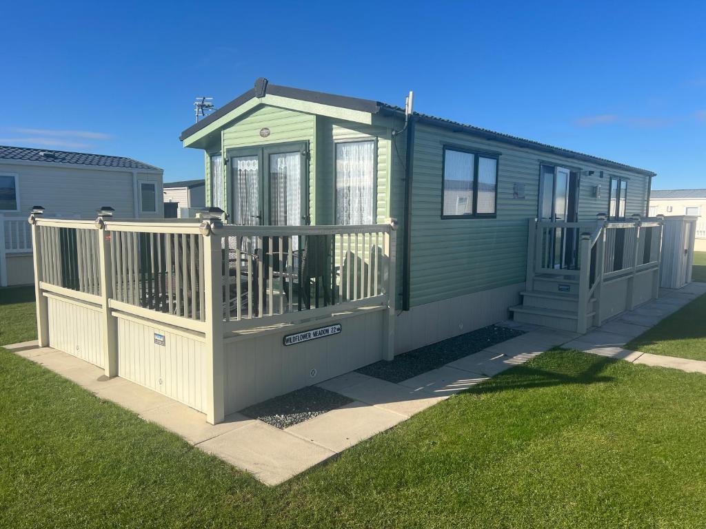 a green house with a porch and a fence at Golden Anchor 6 Berth Caravan, Chapel St Leonards, 22 Wild Flower Meadow in Chapel Saint Leonards