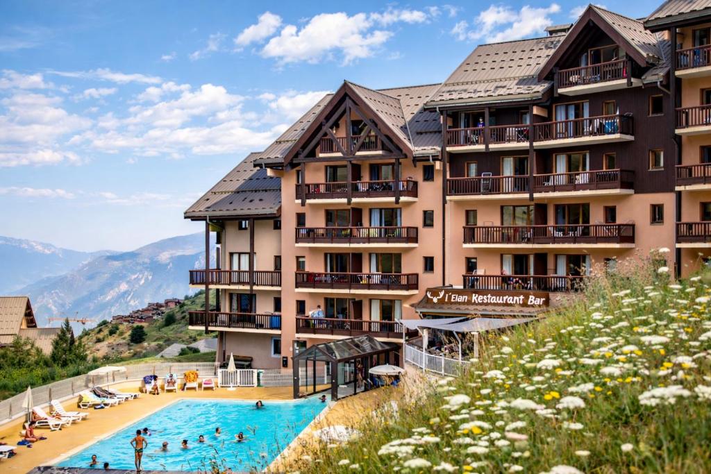 a hotel with a swimming pool in front of a mountain at Résidence Pierre & Vacances Le Thabor in Valmeinier