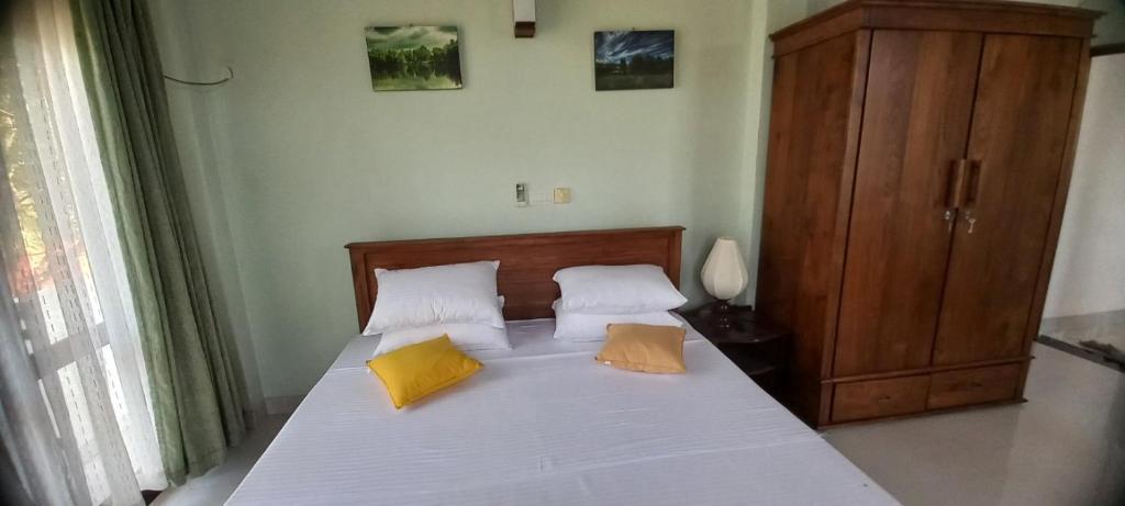 a bedroom with a bed with two yellow pillows at Retraite soleil sérénité in Pamunugama