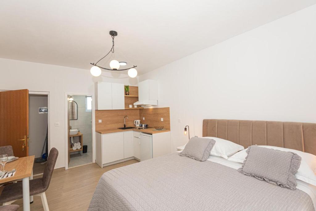 a bedroom with a bed and a table and a kitchen at Studio Apartments Lovrić in Vodice