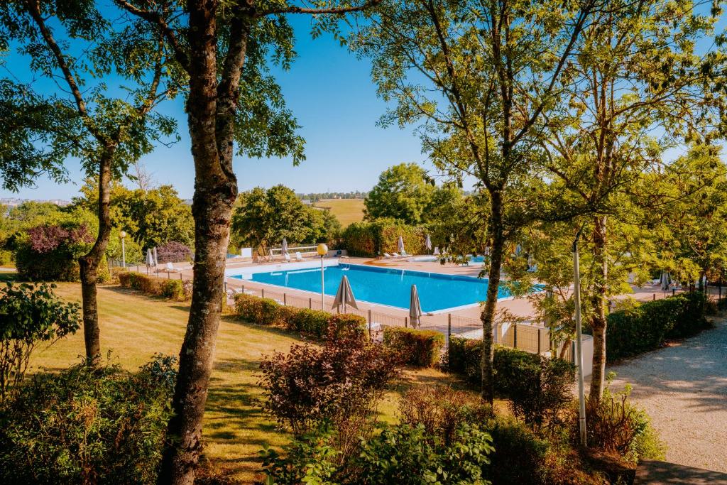 a swimming pool in a park with trees at Village Vacances de Combelles in Le Monastère