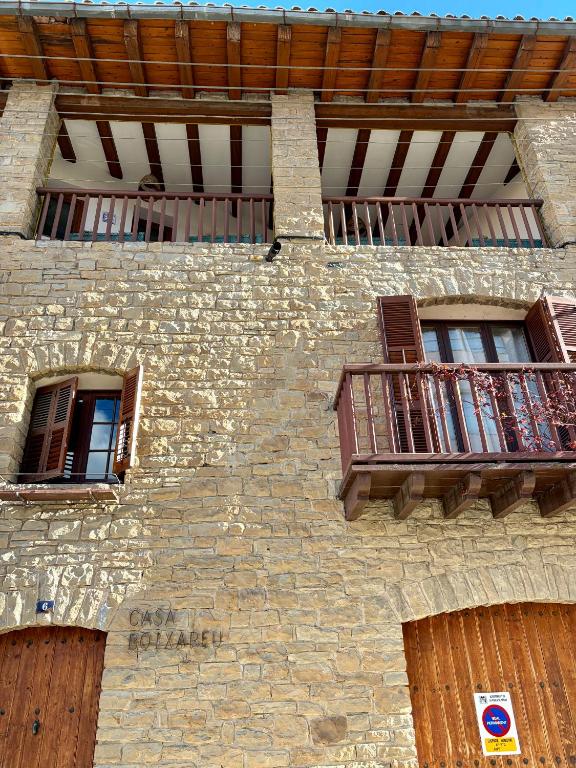 a stone building with two windows and a balcony at Casa Boixareu in La Pobla de Segur