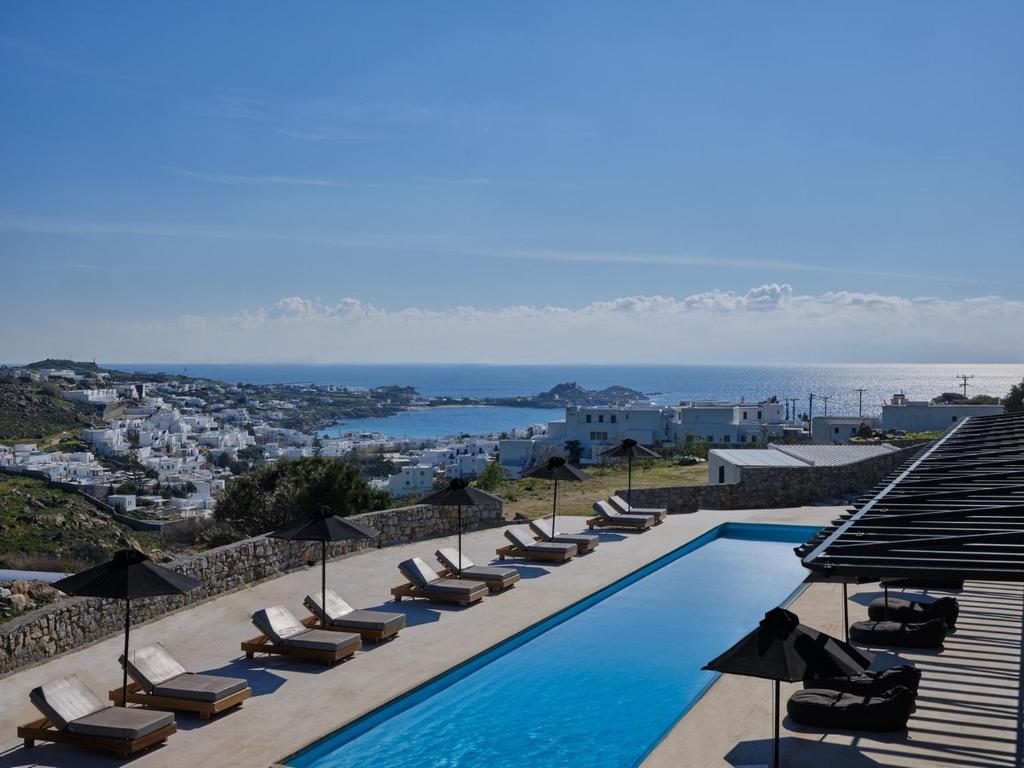 a swimming pool with lounge chairs and umbrellas at Villa Christy in Psarou