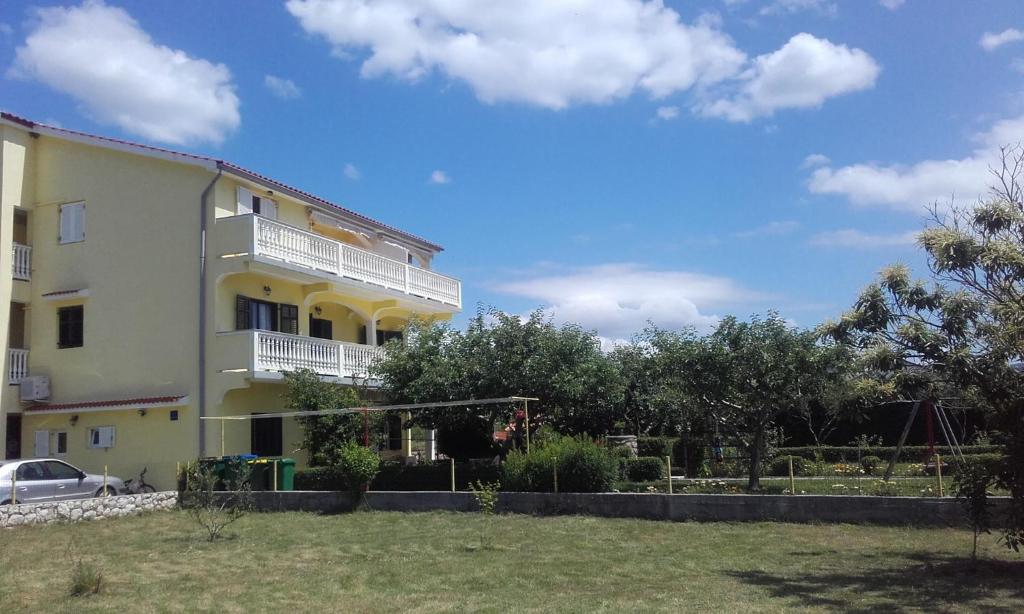 a large yellow building with a yard in front of it at Apartment Lopar 28 in Lopar