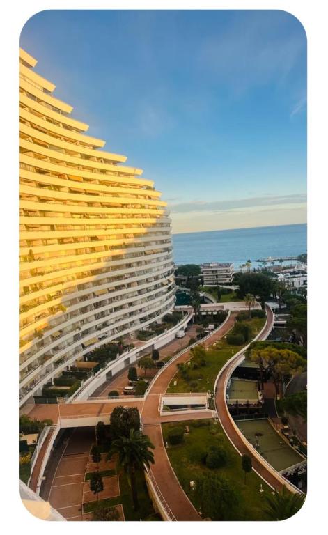 a large yellow building next to a street and the ocean at Casa Monica Nizza VILLENEUVE-LOUBET in La Celle-sous-Gouzon
