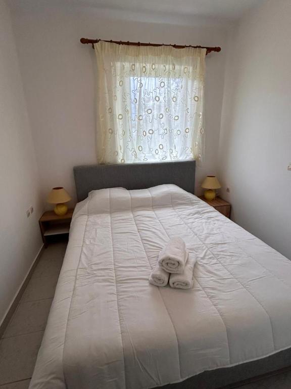 a bedroom with a white bed with towels on it at Seaside Paralio Apartment in Astros