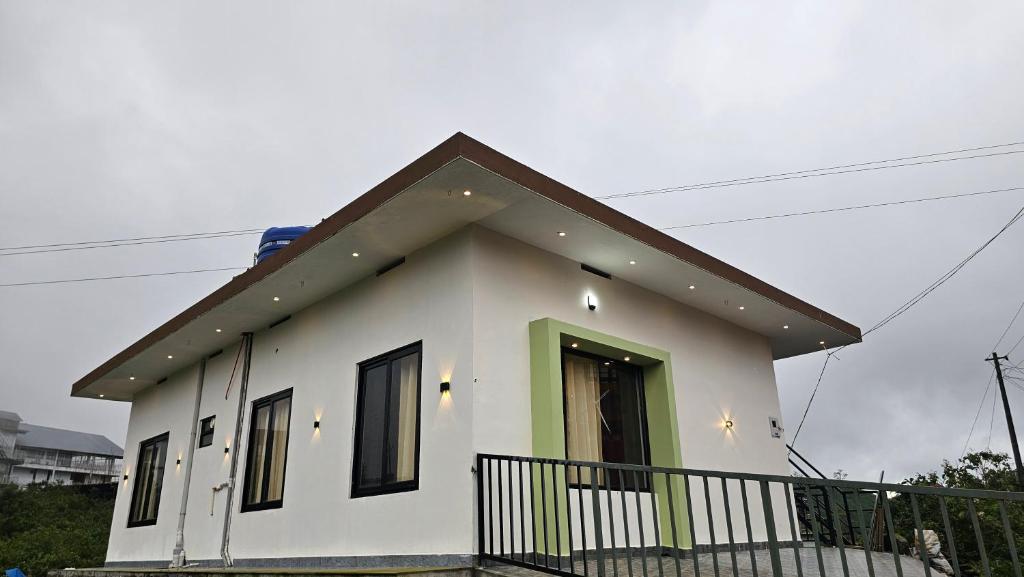 a small white house with a black roof at Moms homestay 3 Bedrooms in Vagamon
