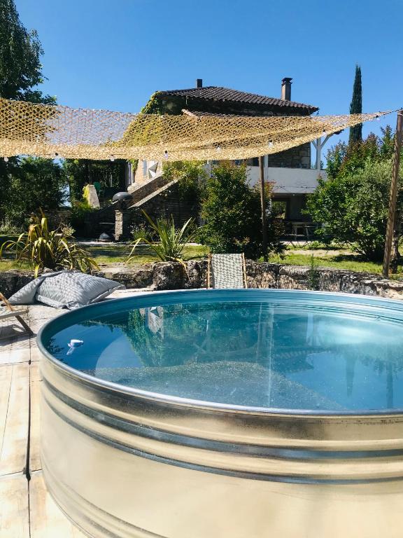 a swimming pool in a backyard with an umbrella at Maison Quercus in Vaylats