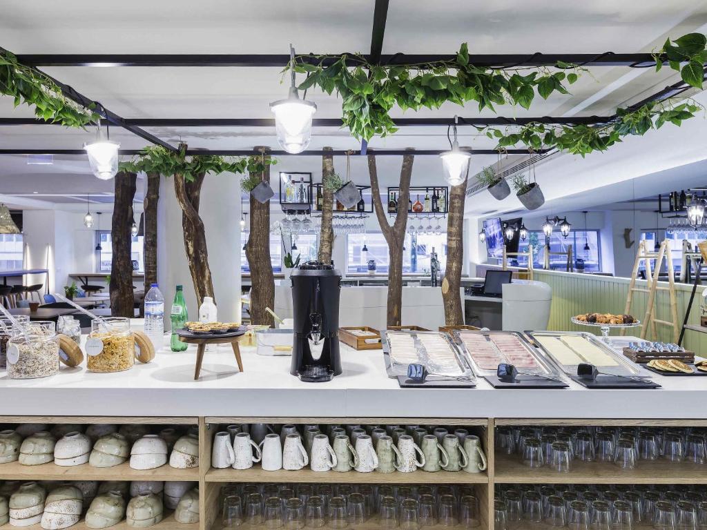 A buffet counter with cereals, serving trays, drinks equipment and extensive cup storage.