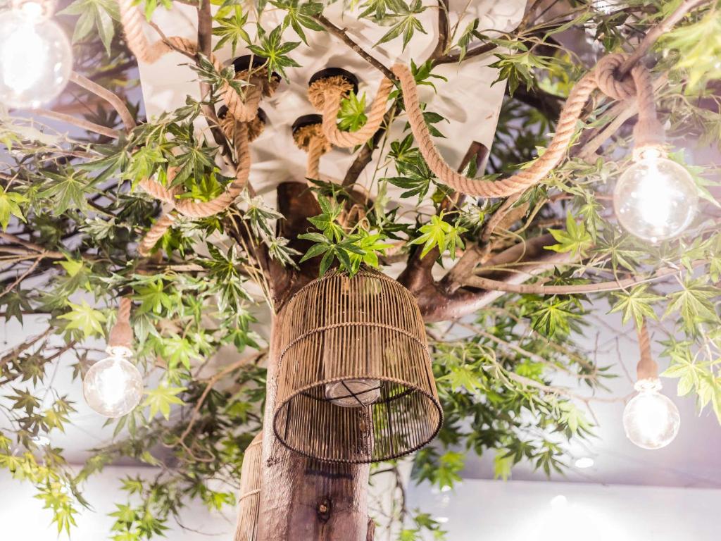 A decorative indoor tree with a hanging birdcage and exposed-style lights.