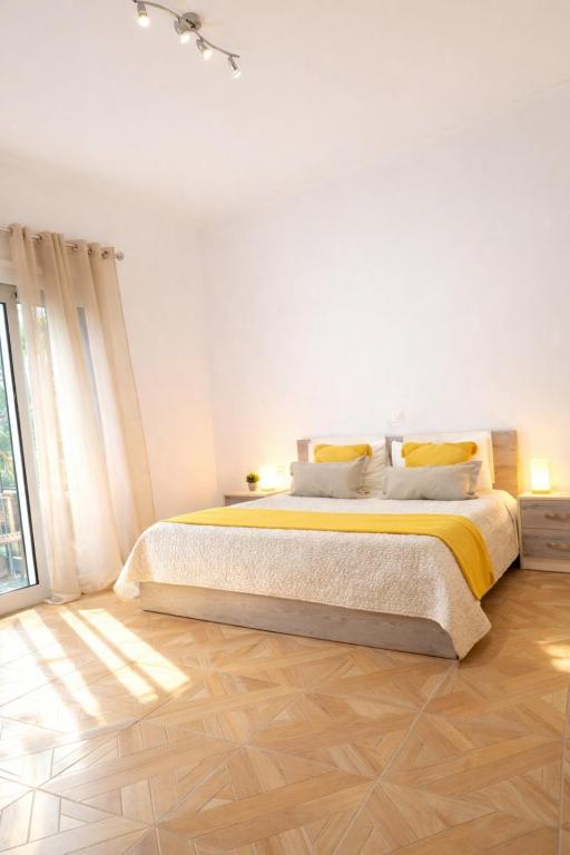 a white bedroom with a large bed with yellow sheets at Dagos Rooms in Dhërmi