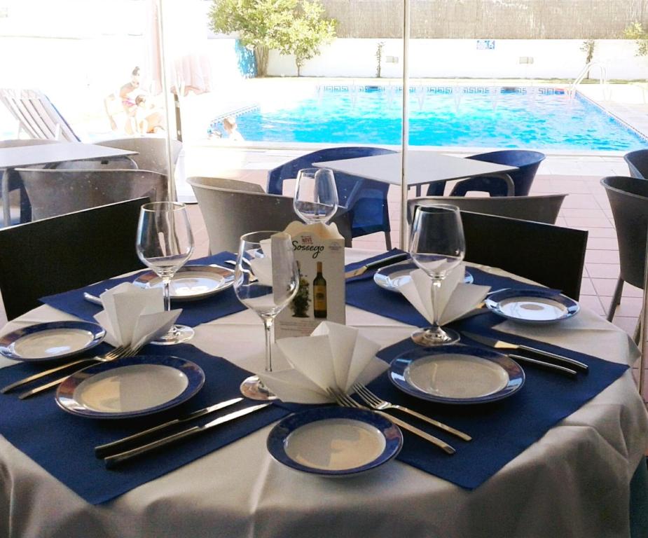 una mesa con platos y copas de vino y una piscina en Vicentina Hotel, en Aljezur