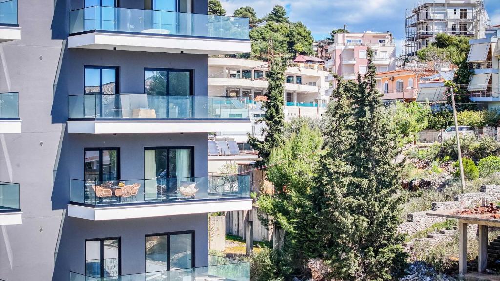 an apartment building with glass balconies and a tree at Seaview Deda 02 in Sarandë
